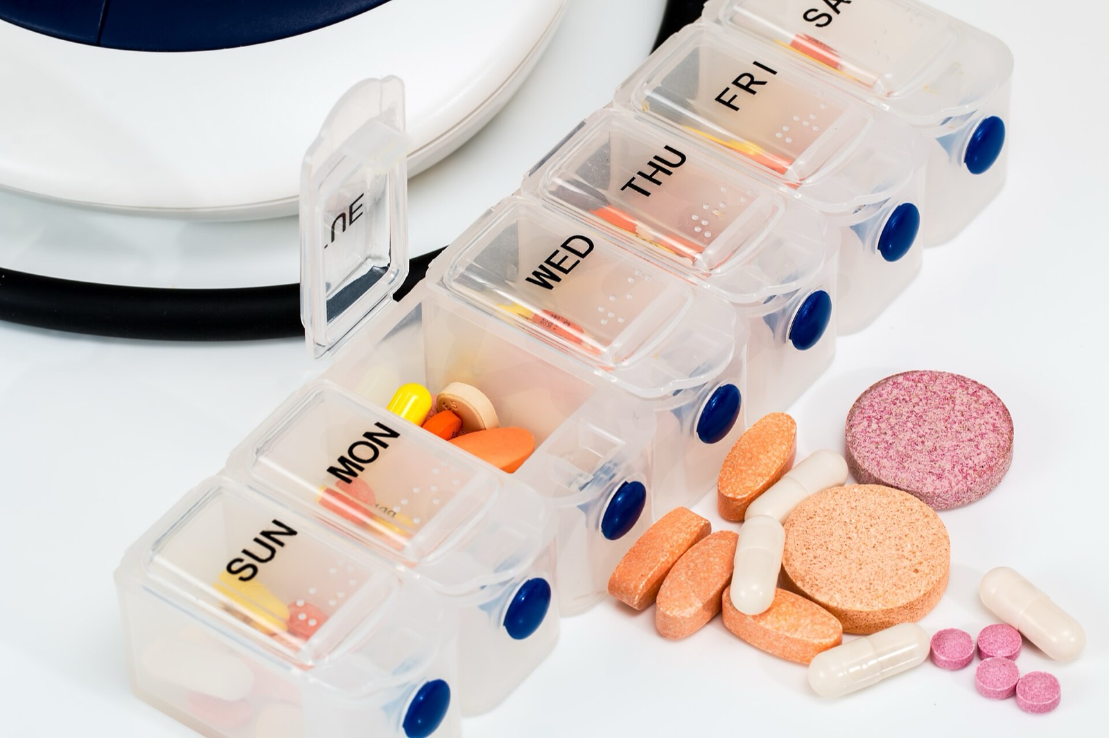 A white weekly pill organiser with colourful tablets in every compartment