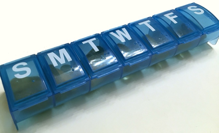 Blue seven-day pill organiser with tablets in each compartment