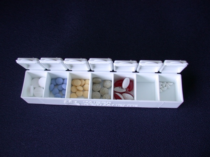 White seven-day pill box filled with assorted medication