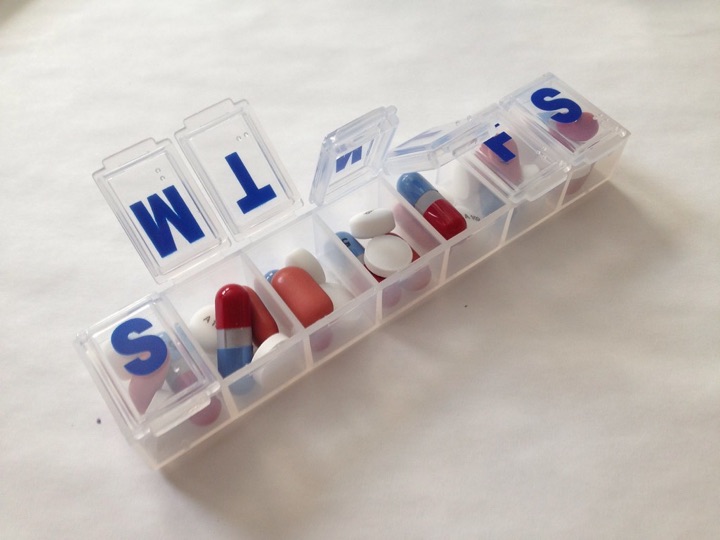 Clear weekly pill organiser with blue day letters and capsules