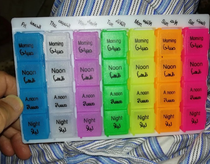 Colourful four-row weekly pill organiser on a striped cloth