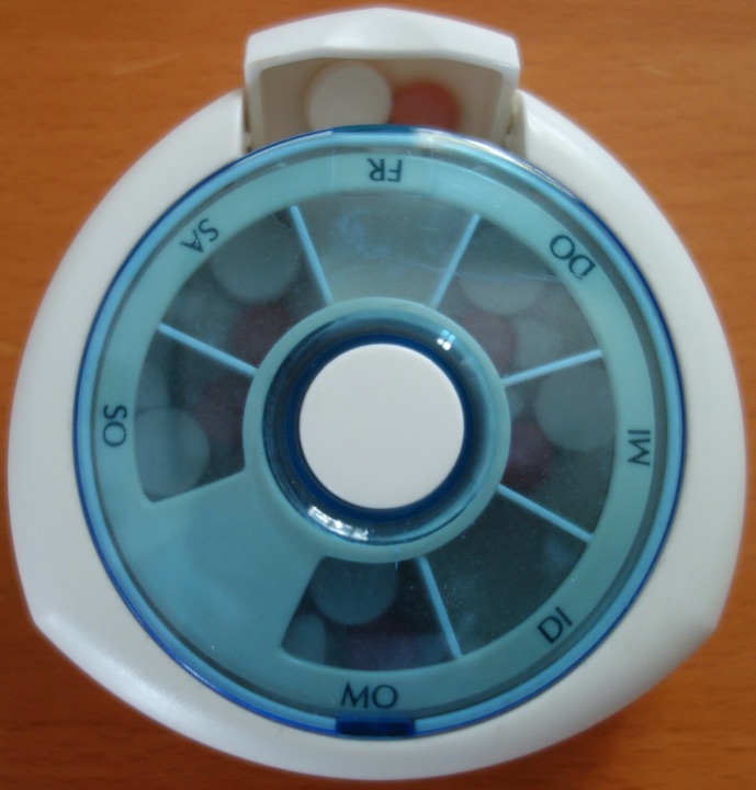 Round weekly pill organiser with a push button in the middle