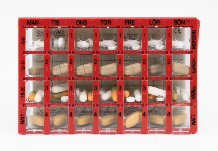 Red seven-by-four pill organiser filled with tablets