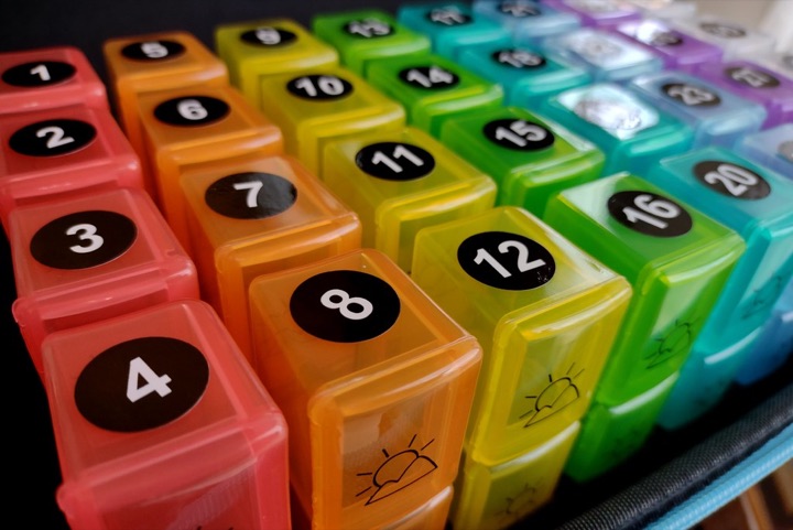 Rainbow-coloured pill boxes stacked close together