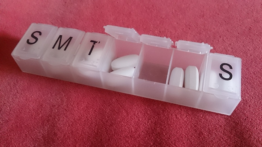 A white weekly pill organiser with two tablets in each compartment